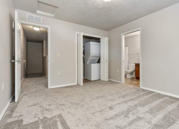 A room with a carpeted floor and a white refrigerator.
