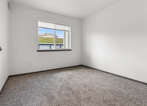 Empty room with a window overlooking a building.