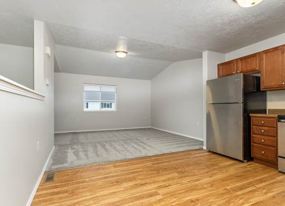 A kitchen area with a refrigerator, microwave, and wooden cabinets.