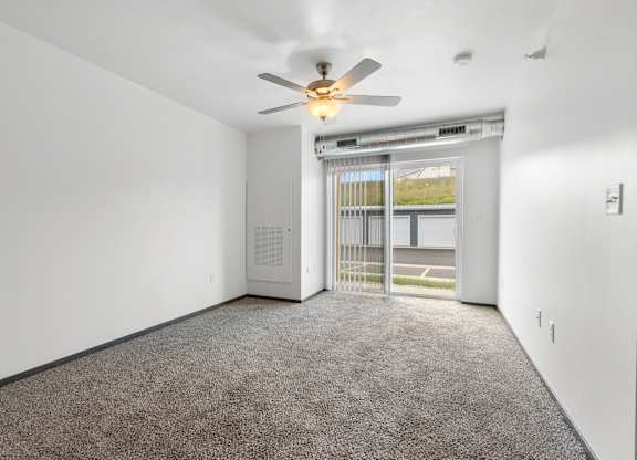 A room with a ceiling fan and carpeted floor.
