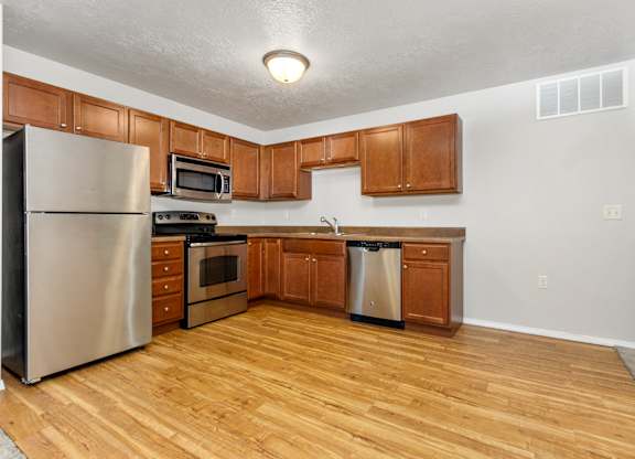 A kitchen with wooden cabinets and a stainless steel refrigerator.