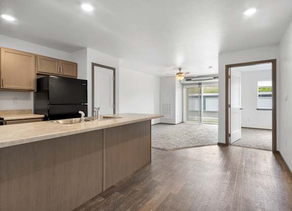 A kitchen with wooden cabinets and a black fridge.