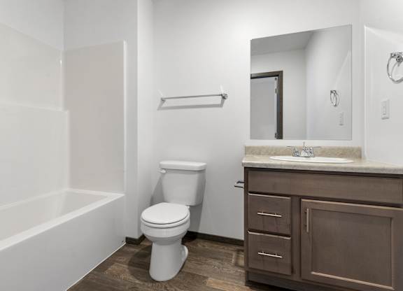 A white toilet sits in a bathroom with a brown cabinet.