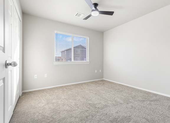 A room with a ceiling fan and a window with blinds.