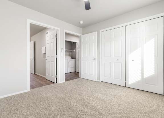 A room with white walls and a carpeted floor with a ceiling fan.