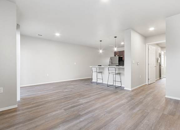 A room with wooden flooring and a kitchenette.