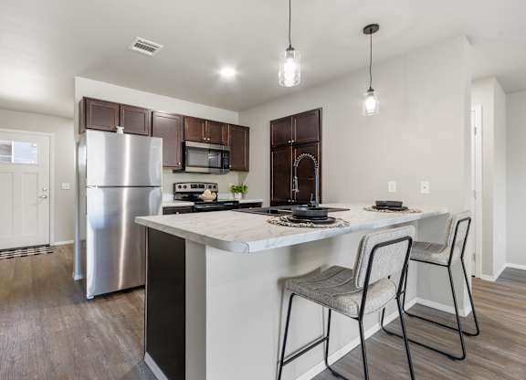 A kitchen with a white island and a stainless steel refrigerator.