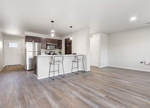 A kitchen with a white counter and bar stools.
