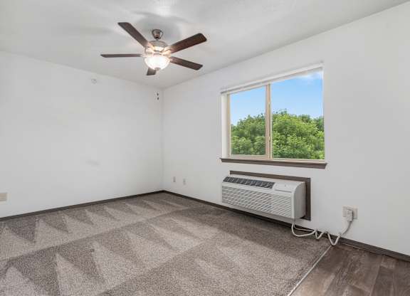 A room with a ceiling fan, a window, and a rug on the floor.