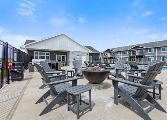 A patio with chairs and a fire pit in front of a building.