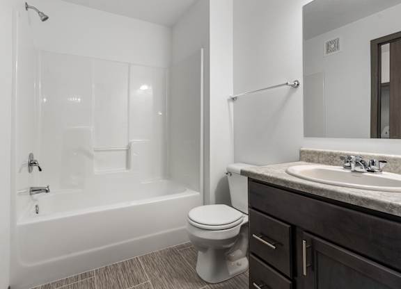 A white toilet sits next to a white bathtub in a bathroom.