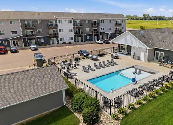 A large apartment complex with a pool and a small house.