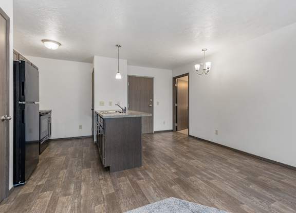 A kitchen with a refrigerator, sink, and cabinets.