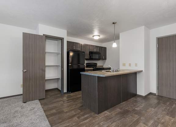 A kitchen with a brown door and a black fridge.