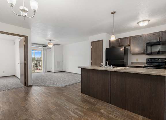 A kitchen with dark wood floors and white walls.
