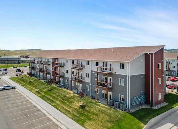 an aerial view of an apartment building with a parking lot and grass