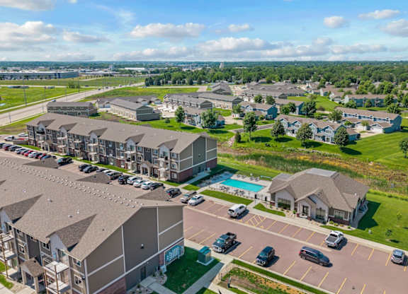 A large apartment complex with a swimming pool and a parking lot.