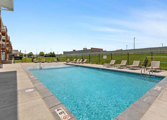 a swimming pool with lounge chairs and a building in the background
