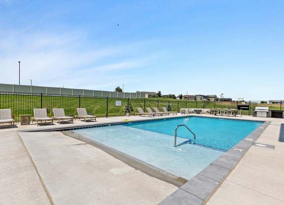 a swimming pool with chairs and a fence around it