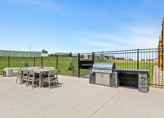 a patio with a grill and a table and chairs