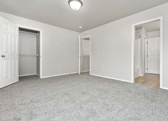 A spacious room with white walls and carpeted floor.