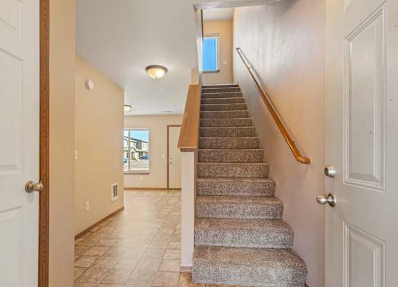 A staircase with a wooden handrail leads to a second floor.