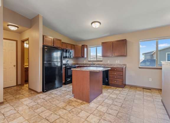 A kitchen with a black refrigerator and wooden cabinets.
