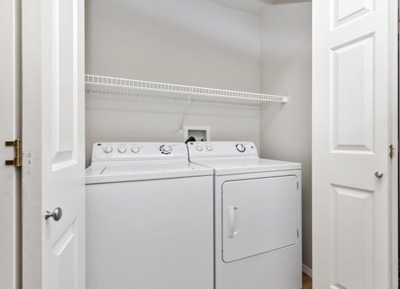 Two white washing machines in a small laundry room.