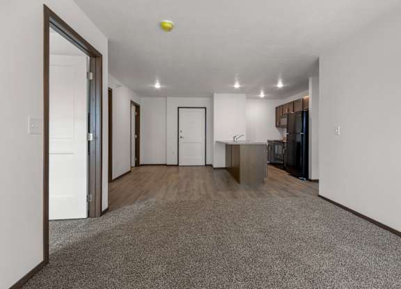 A spacious, empty room with a grey carpet and white walls.
