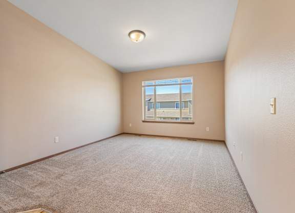 A room with a carpeted floor and a window.