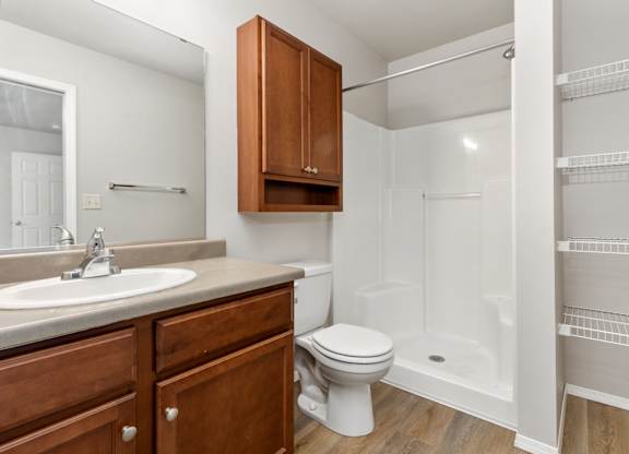 A white bathroom with a toilet, sink, and a walk-in shower.