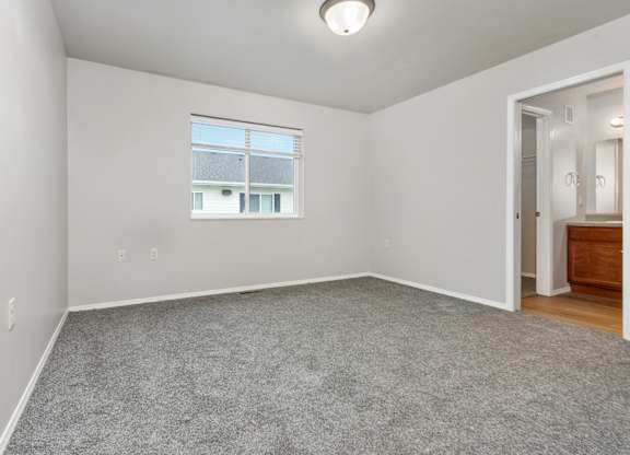 A room with a window and a door leading to another room.