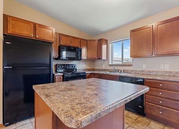 A kitchen with a granite countertop and wooden cabinets.