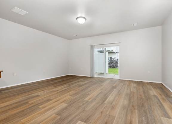 A room with wooden flooring and a sliding glass door.