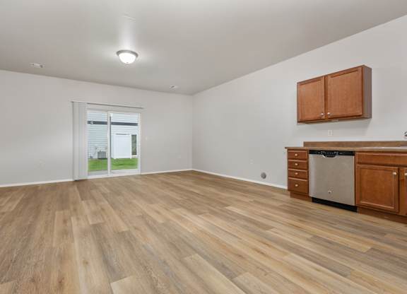 A room with wooden flooring and a window showing a view of a house.