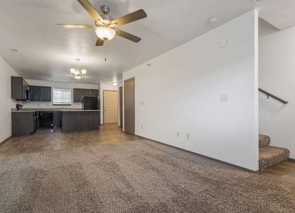 A spacious living room with a ceiling fan and a carpeted floor.