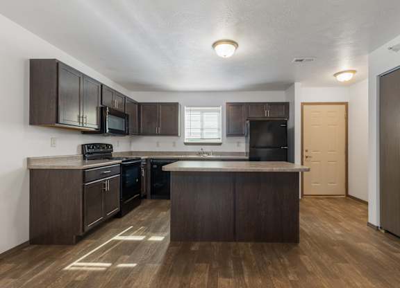 A kitchen with dark wood cabinets and a white countertop.