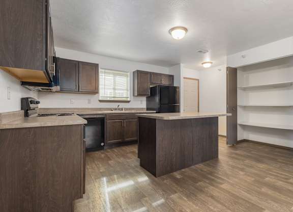 A kitchen with brown cabinets and a wooden floor.