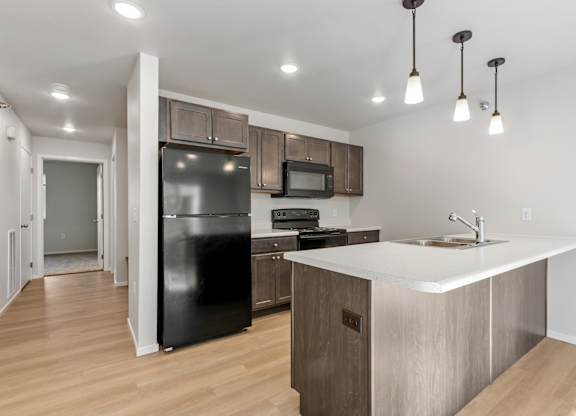 A kitchen with a black fridge, microwave, and stove top oven.