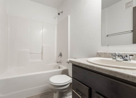 A white toilet sits next to a white bathtub in a bathroom.