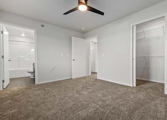 A room with a ceiling fan and carpeted floor.