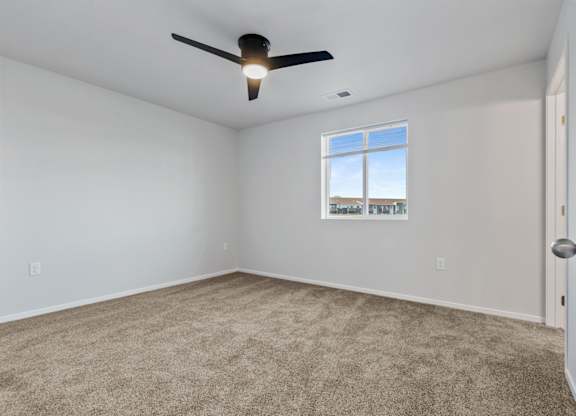 A room with a ceiling fan and a window showing a view of a building.