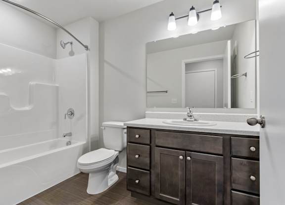 A bathroom with a white tub, sink, and toilet.