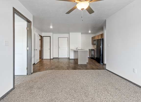 A spacious room with a ceiling fan and a carpeted floor.