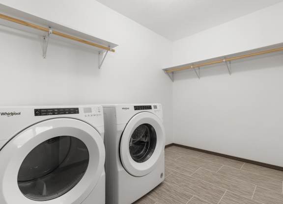 Two white front loading washing machines in a laundry room.