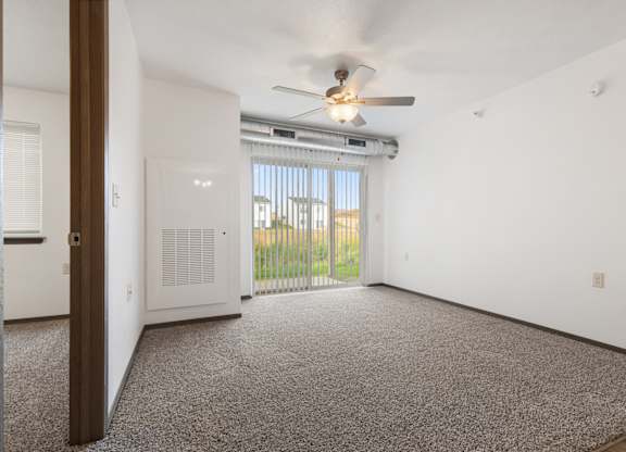 A room with a ceiling fan and a window with blinds.