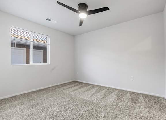 A room with a ceiling fan and carpeted floor.