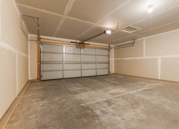 A garage with a white door and a brown floor.