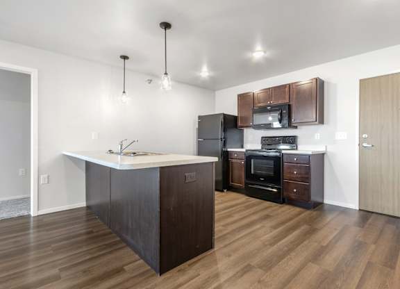A kitchen with dark wood floors and a white island.