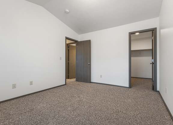 A room with a carpeted floor and a door on the left.